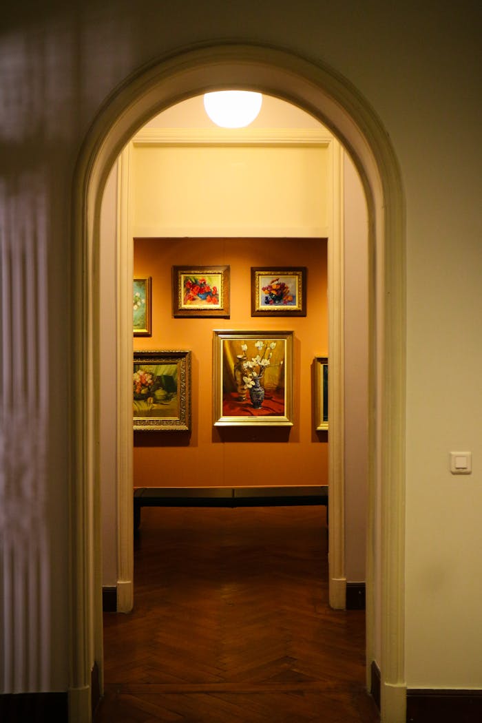Services A well-lit corridor leading to an art gallery display with elegant framed paintings.